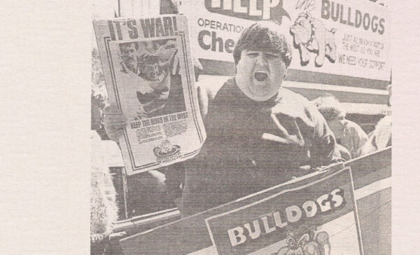Man holds up protest posters about the closure of the football club