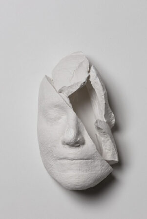 A photo of a plaster sculpture of a head with a smashed side.